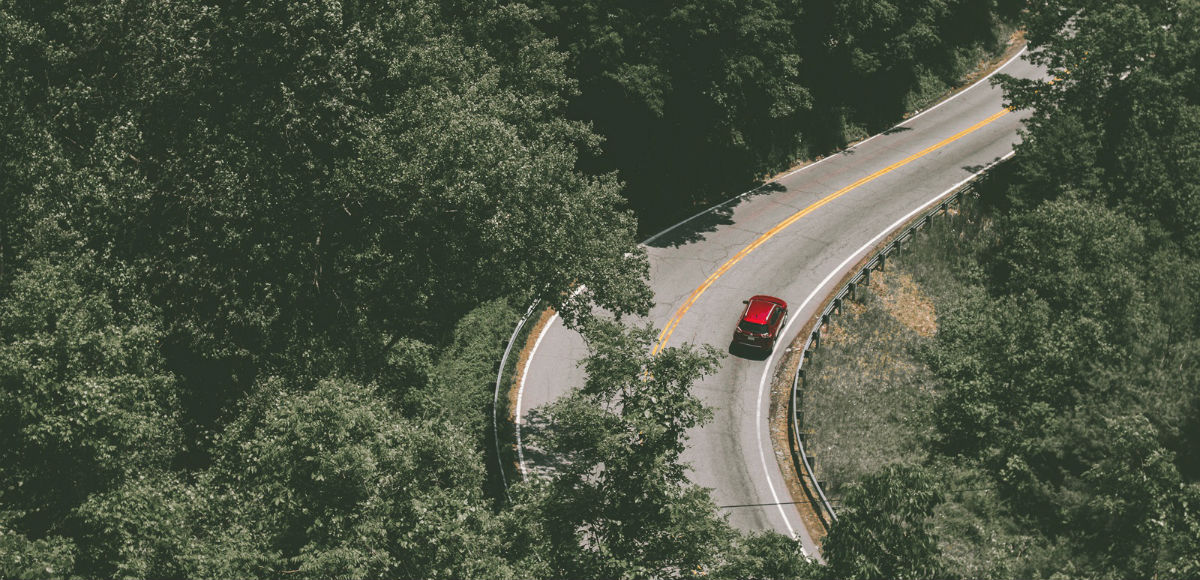 Symbolbild: Ein rotes Auto fährt eine Bergstraße hinauf