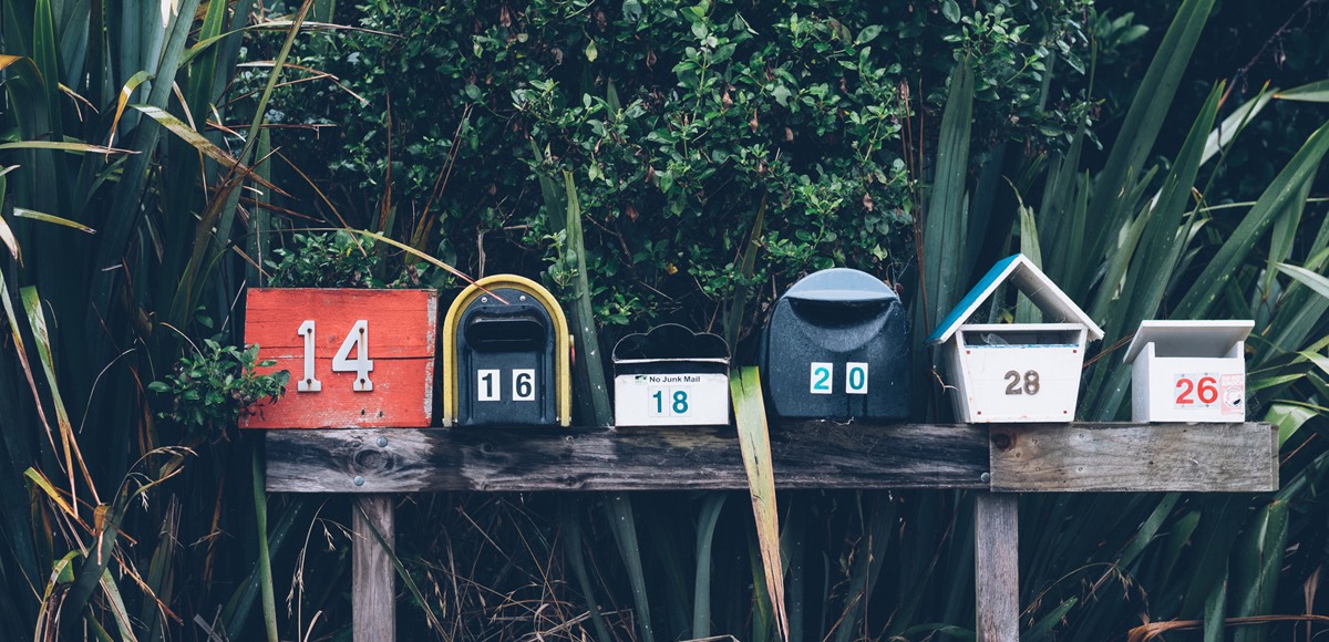 Symbolbild: Eine Reihe Briefkästen auf einem Holzbrett