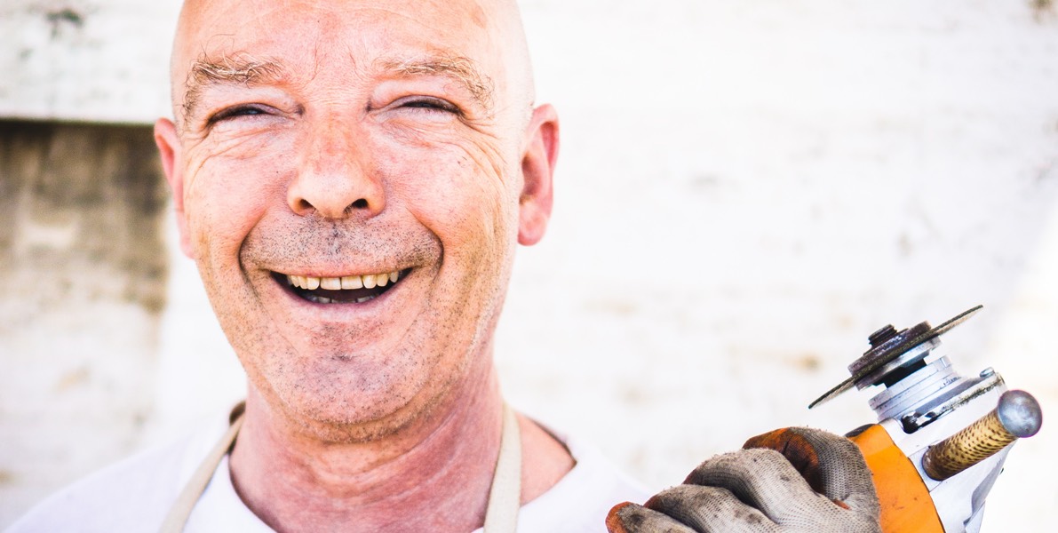 Symbolbild: Ein lachender Mann mit Trennschleifer in der Hand