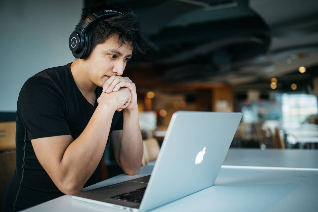 start_academy Symbolbild: Ein junger Mann sitzt mit Kopfhörern konzentriert vor einem Notebook