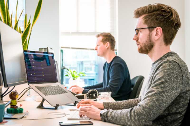 Office People Symbolbild: Ein junger Mann sitzt mit Kopfhörern konzentriert vor einem Notebook