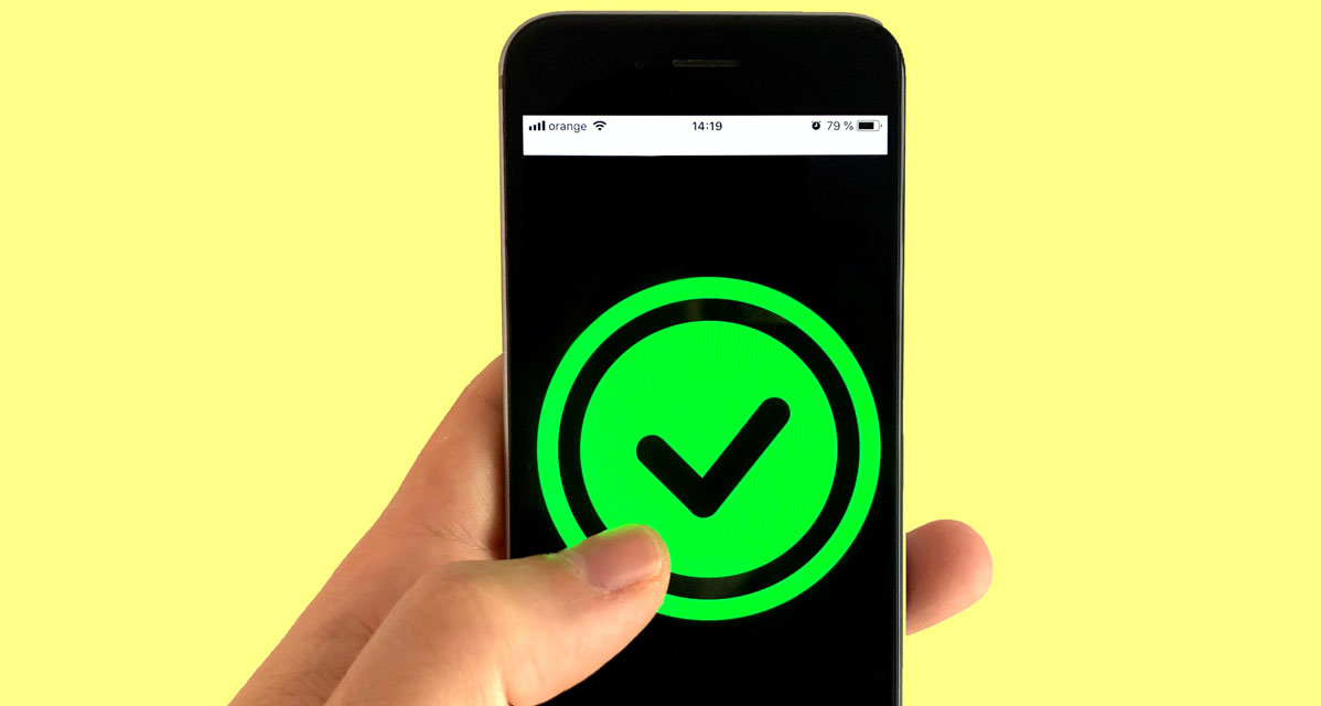 Symbolbild: Smartphone mit einem grünen Haken, der von einem Daumen gedrückt wird